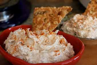 A cup of blue crab dip with a chip in it