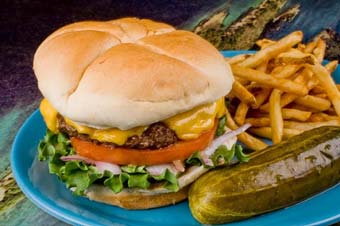 A cheeseburger with a pickle and fries