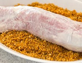 A piece of pork sitting in a bowl of Panko